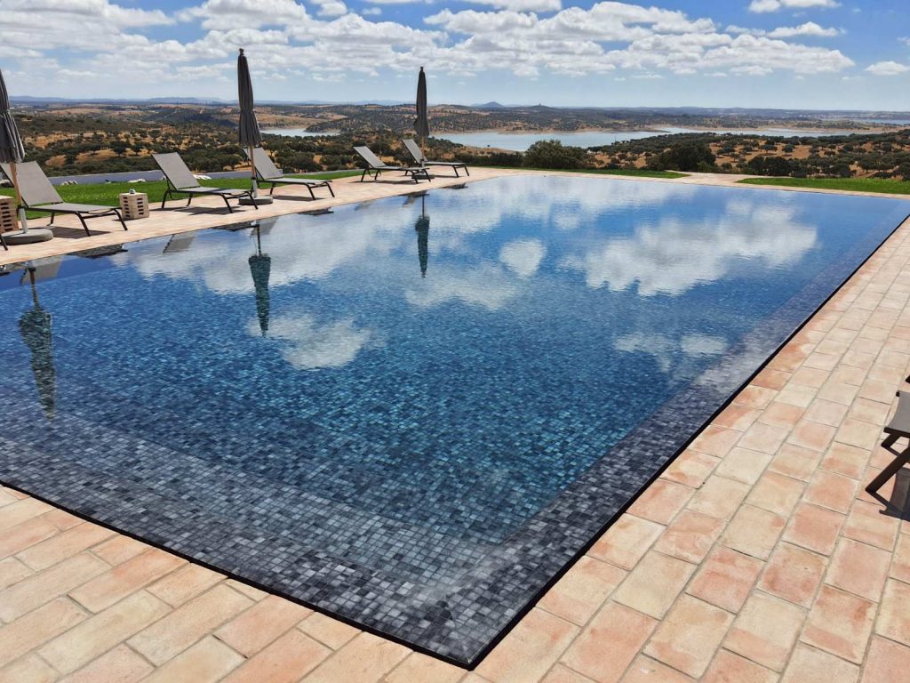 Revestimento de piscina com transbordo total em Monsaraz. Estética preto e branco com pastilha Hisbalit Niebla 101 e betume epóxi preto Kerakoll.