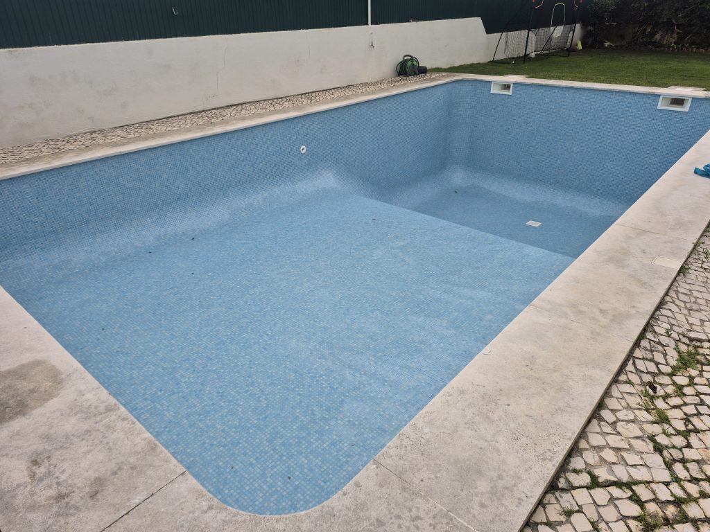 Vista geral de piscina restaurada com pastilha azul nova e juntas limpas